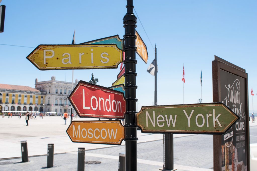 Bunte Wegweiser zeigen in die Richtungen Paris, London, Moscow und New York.